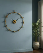 Gold wall clock on a blue wall with a plant in the corner