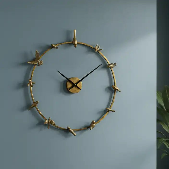 Decorative wall clock with gold branch design on a blue wall