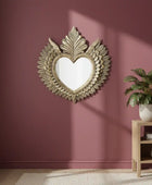 Decorative heart-shaped mirror with floral details on a maroon wall.