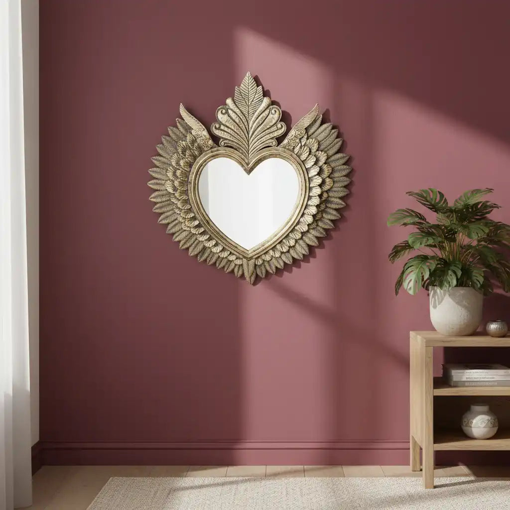 Decorative heart-shaped mirror with floral details on a maroon wall.