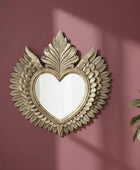Decorative heart-shaped mirror with floral details on a pink wall.