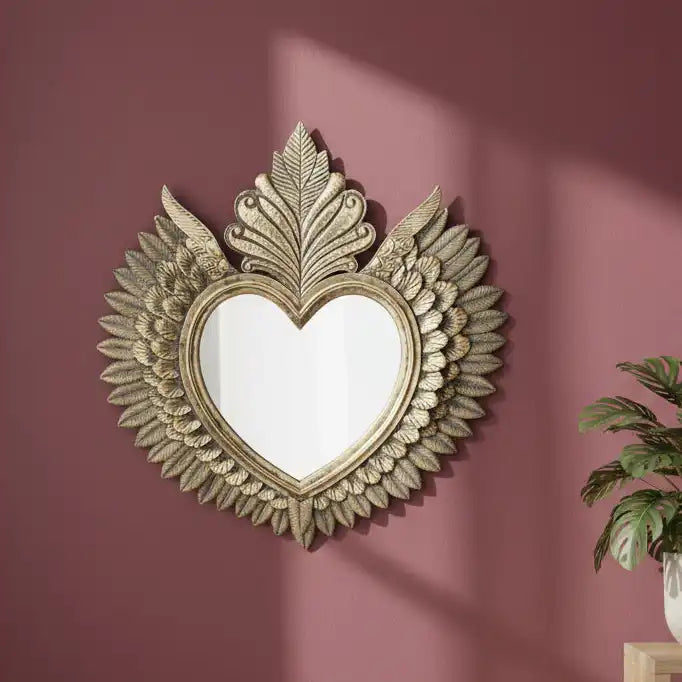 Decorative heart-shaped mirror with floral details on a pink wall.