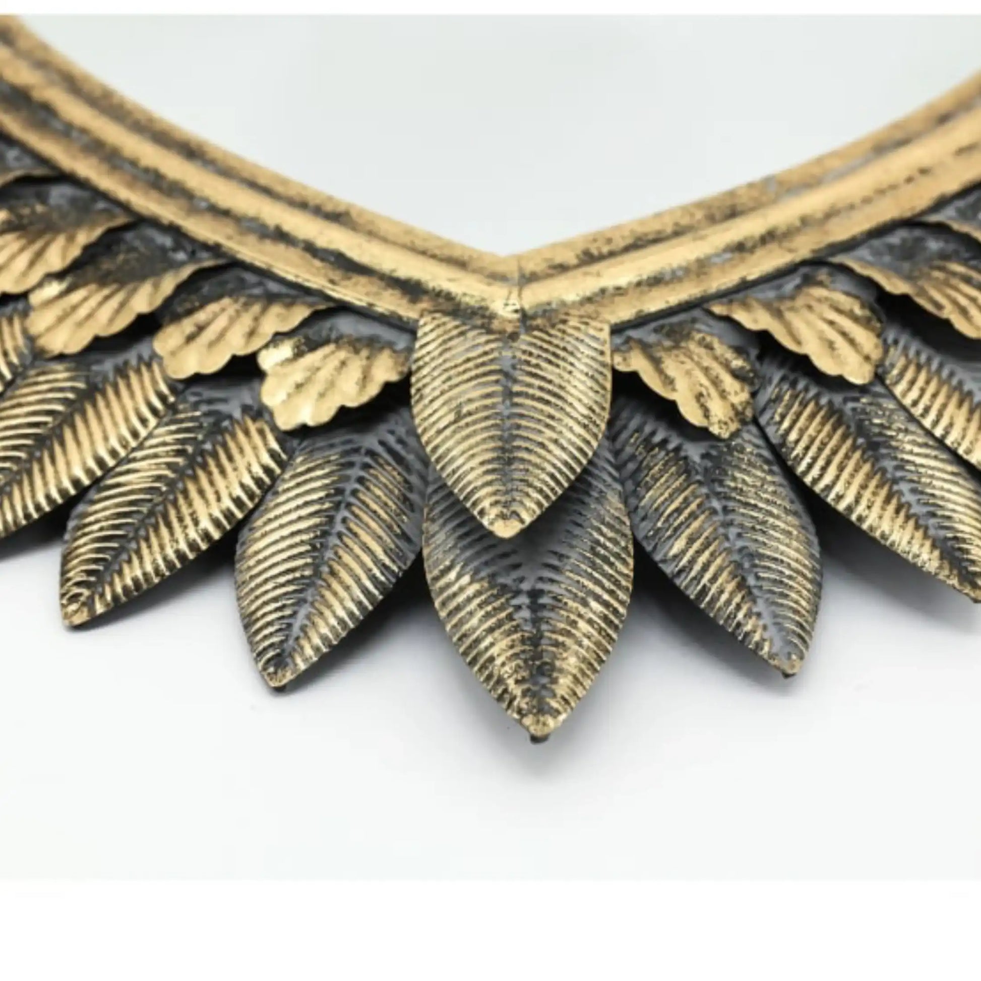 Close-up of a gold and silver leaf-patterned necklace on a white background