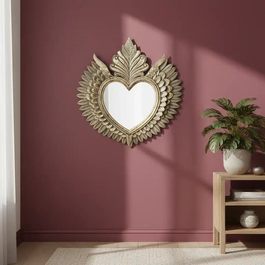 Decorative heart-shaped mirror with floral details on a maroon wall.