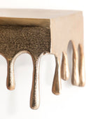 Close-up of a bronze-colored metal object with dripping design on a white background