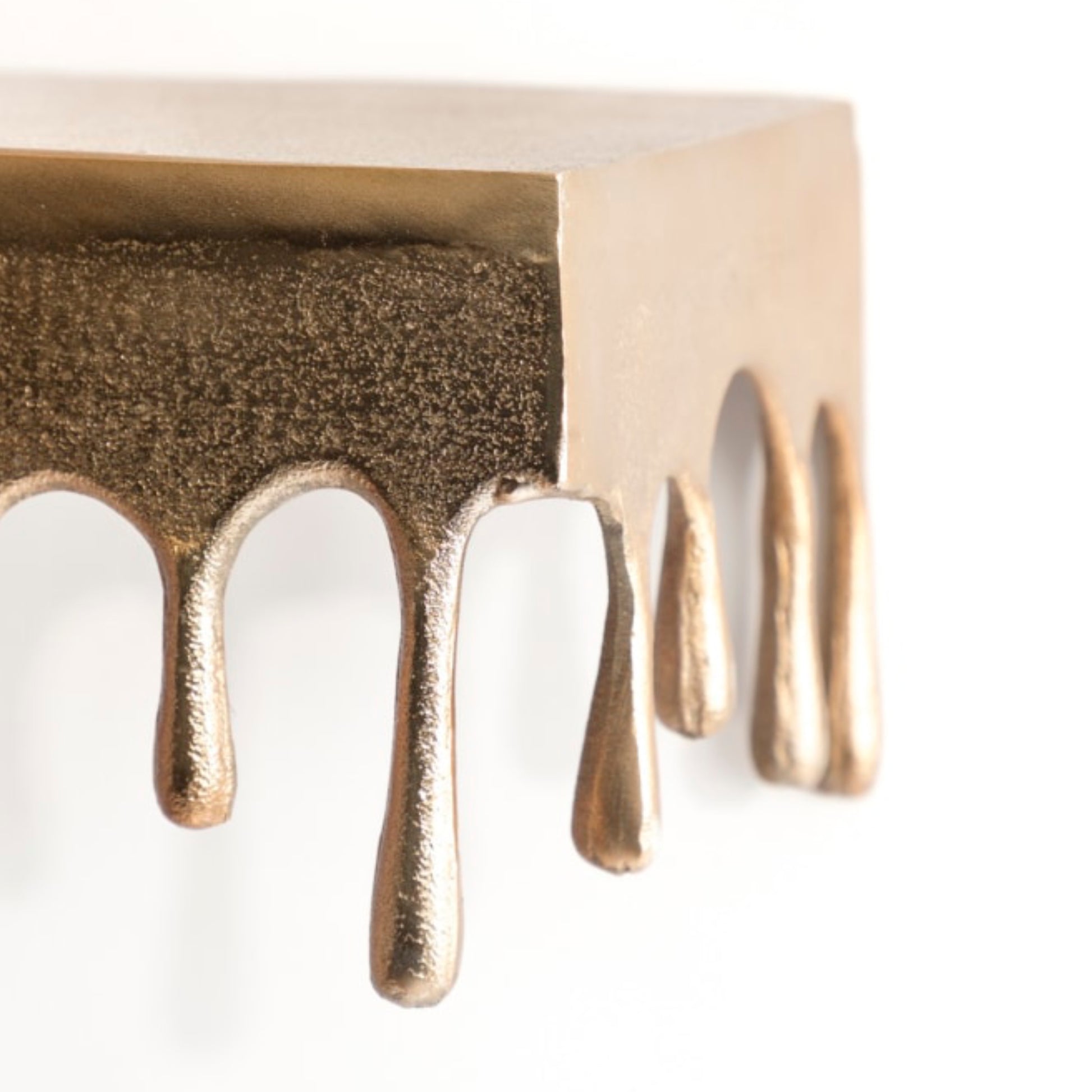 Close-up of a bronze-colored metal object with dripping design on a white background