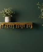 Gold decorative shelf with a potted plant against a dark green wall