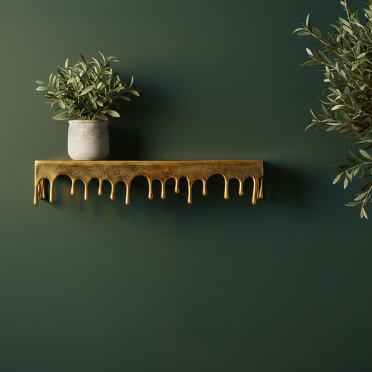 Gold decorative shelf with a potted plant against a dark green wall