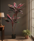 Decorative plant in a room with a desk, lamp, and bookshelf.