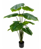 An artificial monstera plant with large green leaves in a black pot, isolated on a white background.