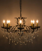 Crystal chandelier with six lit candles against a dark background