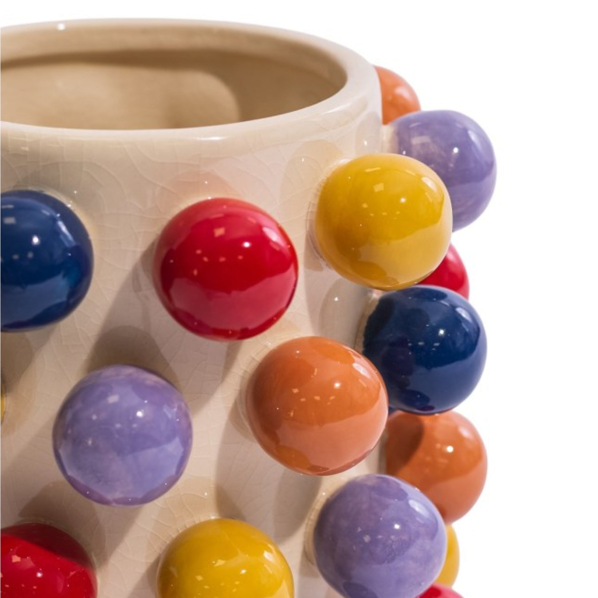Close-up of a ceramic mug with a cream-colored glaze and raised, glossy multicolor spherical accents in red, yellow, blue, purple, and orange on a white background.