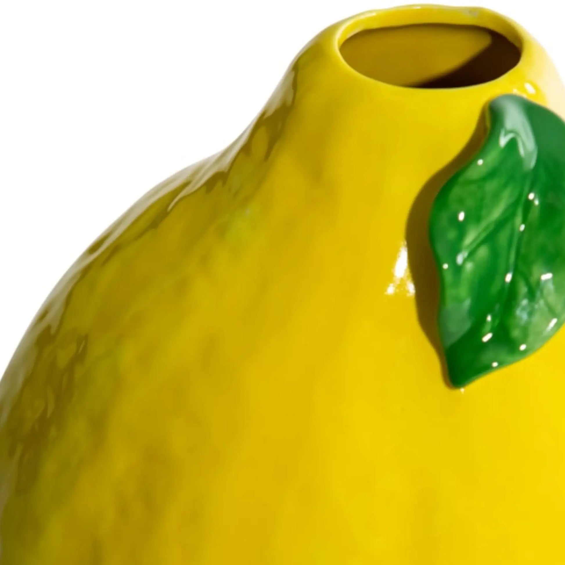 Yellow ceramic vase with a green leaf on a white background