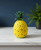 Yellow pineapple-shaped container on a marble surface with a dark blue background