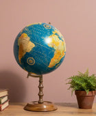 Vintage-style globe on a wooden surface with books and a plant