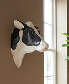 Decorative cow head wall art on a wall with a window and plant in the background