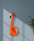 Decorative flamingo wall art against a gray wall with a plant on the right.