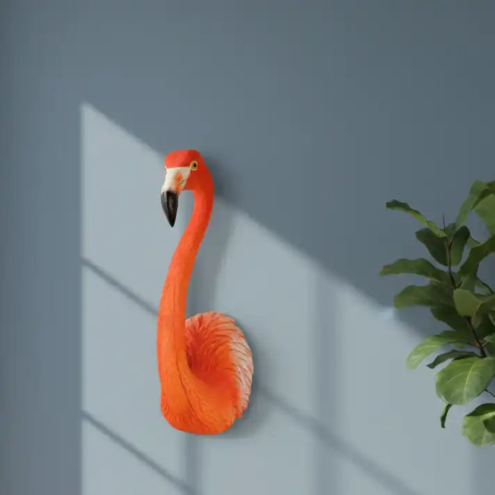 Decorative flamingo wall art against a gray wall with a plant on the right.