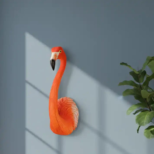 Decorative flamingo wall art against a gray wall with a plant on the right.