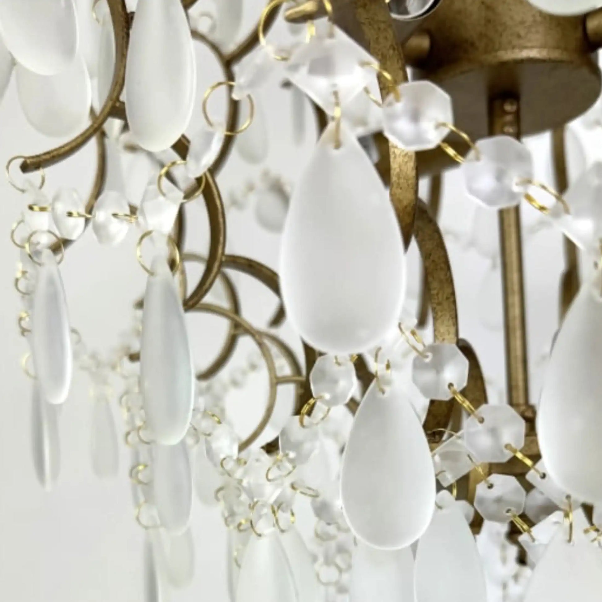 Close-up of a chandelier with white teardrop crystals and gold accents.
