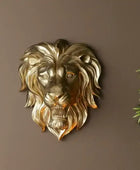 Gold lion head wall decoration on a brown wall with a plant in the corner