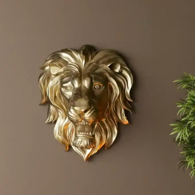 Gold lion head wall decoration on a brown wall with a plant in the corner