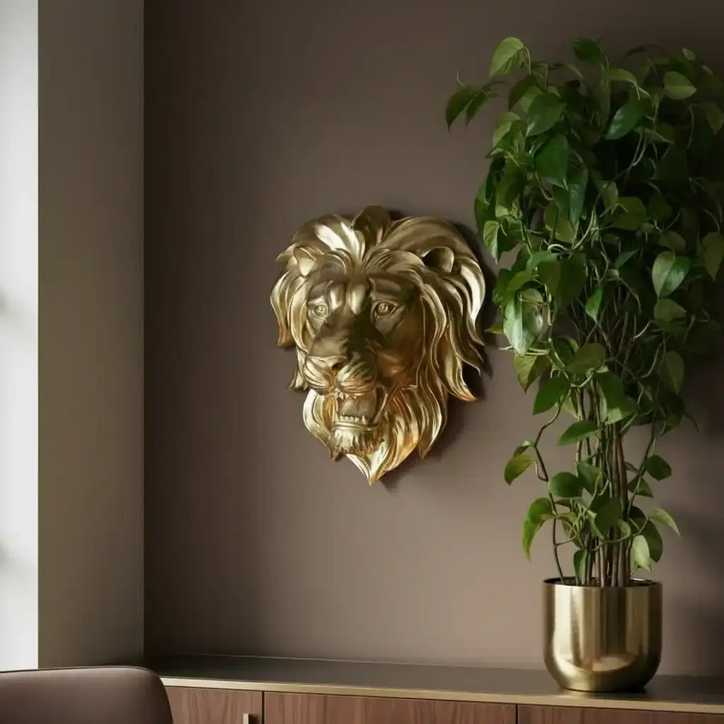 Gold lion head wall decoration next to a potted plant on a shelf against a brown wall.