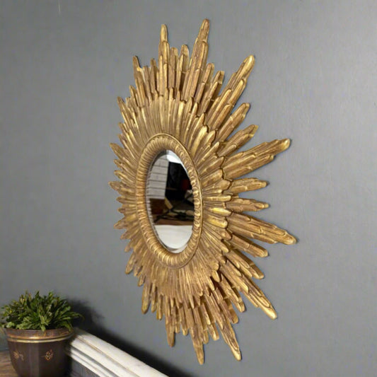 Decorative gold sunburst mirror on a gray wall