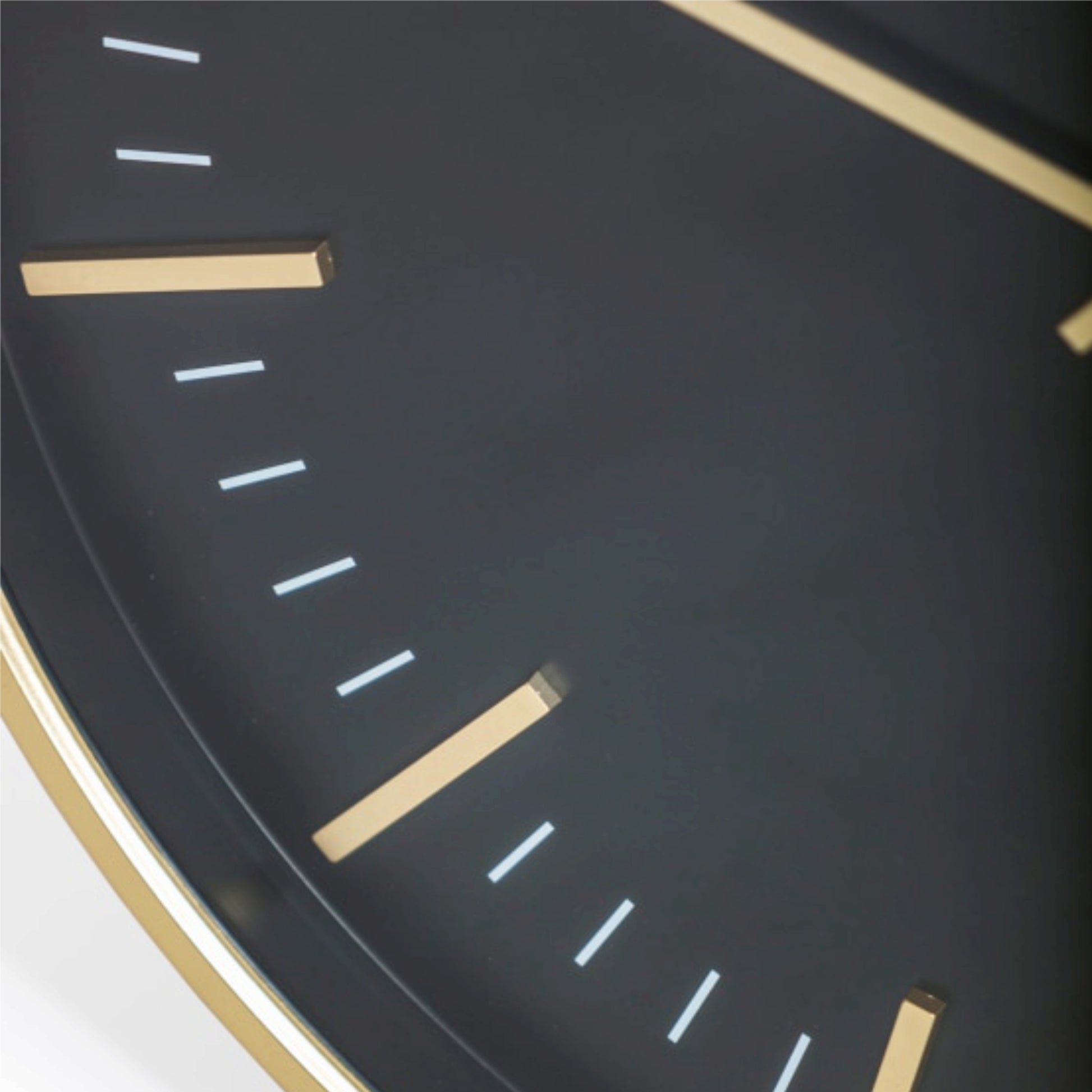 Close-up of a clock face with gold hour markers on a dark background