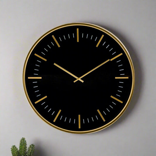 Black wall clock with gold accents on a gray background