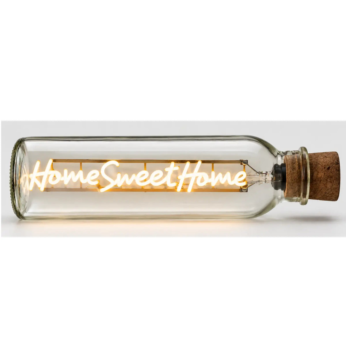 A clear glass bottle-style light with a cork stopper, glowing with warm yellow light and the words 'Home Sweet Home' across the front, shown on a plain light background.
