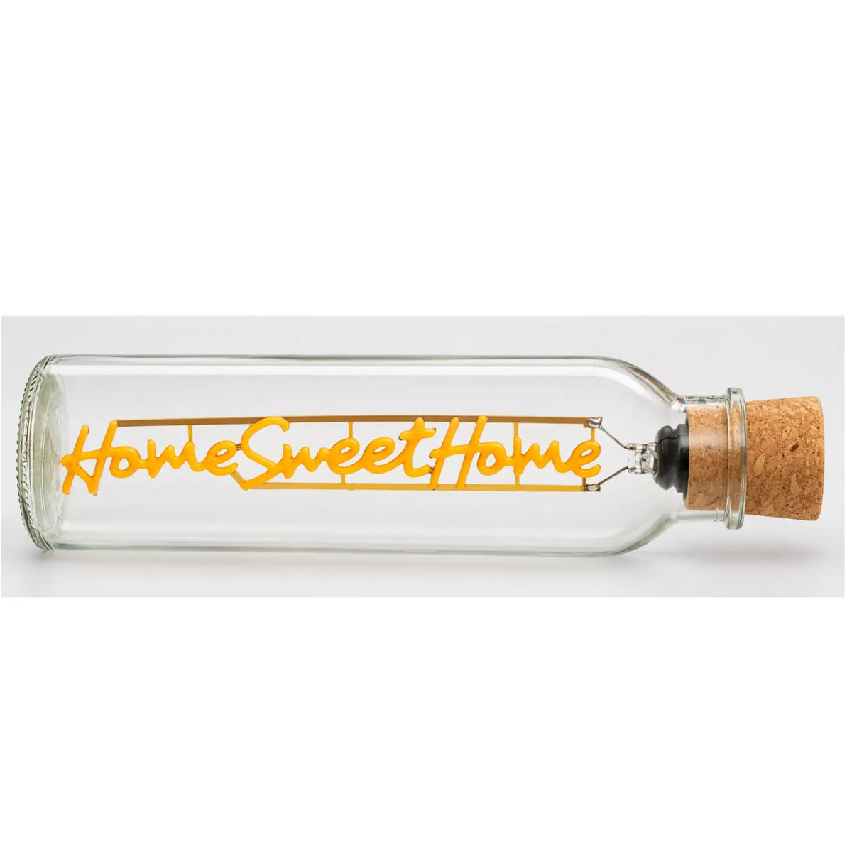A clear glass bottle with a cork stopper, featuring a warm yellow-orange LED light string that spells out 'Home Sweet Home' in script and block lettering.
