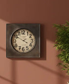 Decorative wall clock on a brown wall with a plant to the right