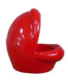 Red ceramic chair with a unique design on a wooden surface and stone wall background