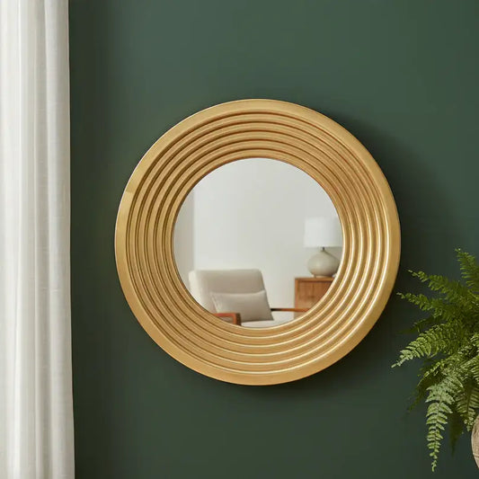 Round wooden mirror on a green wall with a chair and lamp in the reflection