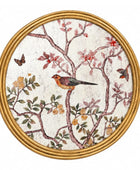 Round framed wall art featuring a botanical and bird illustration with a bird perched on branches, flowers, leaves, and butterflies on a textured off-white background, surrounded by a gold-toned frame.