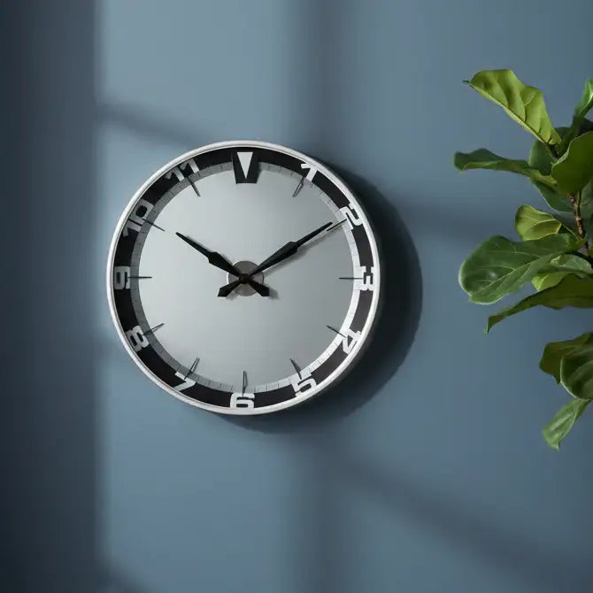 Wall clock on a blue wall with a plant to the right