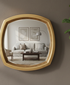Gold-framed mirror reflecting a living room with a sofa and coffee table.