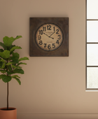 Decorative wall clock on a beige wall with a plant to the left