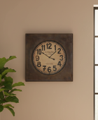 Decorative wall clock on a beige wall with a plant to the left.