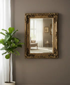 Decorative mirror with gold frame on a wall next to a potted plant