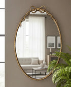 Gold-framed mirror on a wall with a living room in the background