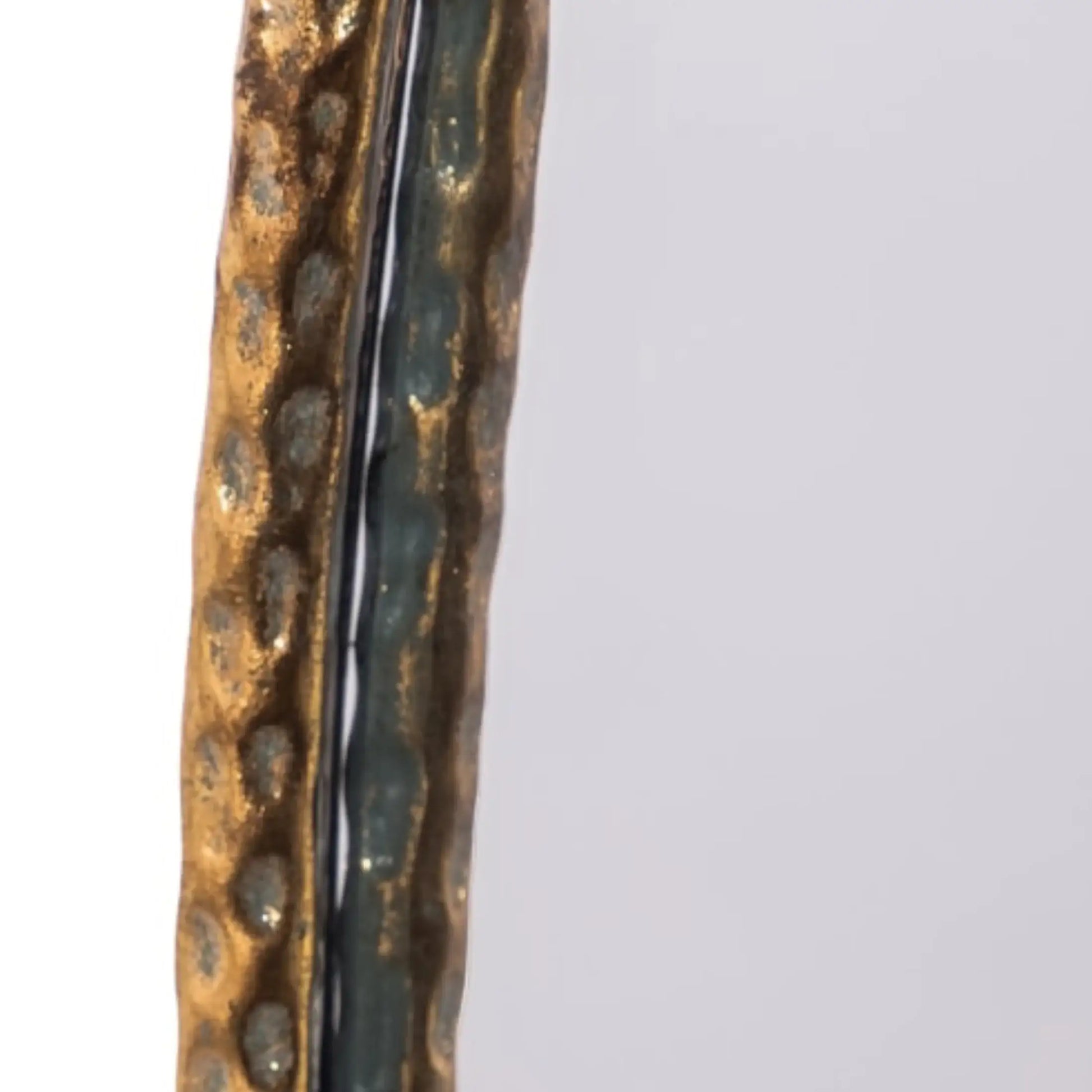 Close-up of a textured bronze or copper object on a light gray background