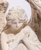 Statue of a cherub with detailed carvings on a white background