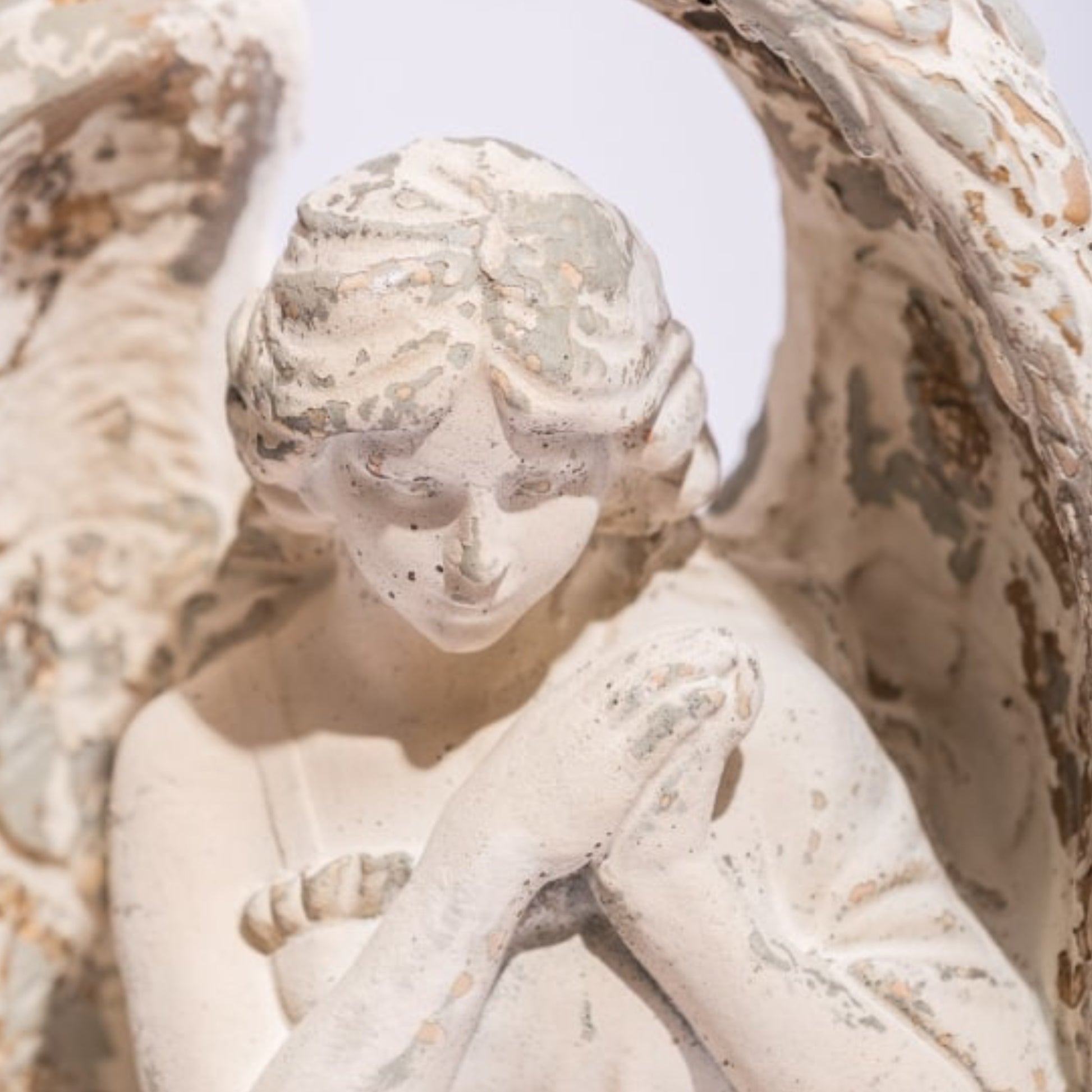 Statue of a cherub with detailed carvings on a white background