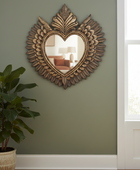 Decorative heart-shaped mirror with intricate design on a green wall.