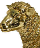A close-up of a metallic gold sheep figurine, showing its textured wool and detailed head profile against a plain white background.