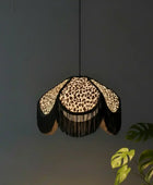 Leopard print pendant light with black fringe against a dark background