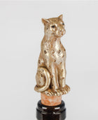 A metallic gold leopard-shaped bottle stopper with spotted detailing, mounted on a cork and dark glass bottle against a light gray background.
