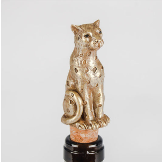 A metallic gold leopard-shaped bottle stopper with spotted detailing, mounted on a cork and dark glass bottle against a light gray background.